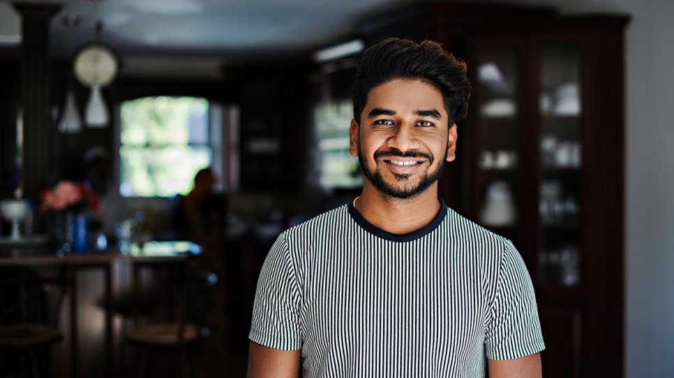 Rohingya refugee Faisal Mohammed, 24, stands in his dining room in Kitchener, Ontario. Faisal's parents lost five children to sickness or hunger before fleeing Myanmar for Bangladesh while Faisal's mother was pregnant with him. He is one of 14 refugees who contributed recipes to 'Tastes from Home.'