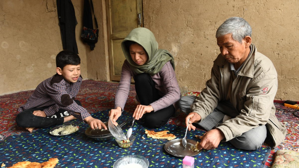 Twenty-seven-year-old Afghan returnee Kobra Yusufy eats lunch with her brother Mahdi, 11, and father Mohammad, 56, in their living room in Kabul.