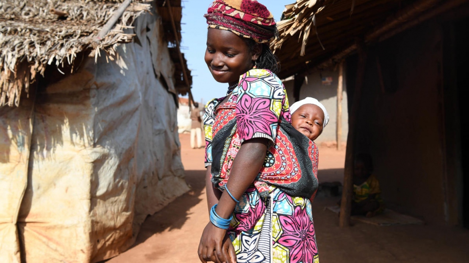 A young girl holds her little brother on her back at Mbile refugee site, one of several sites in the East Region where the kangaroo care method is saving the lives of prematurely-born babies.