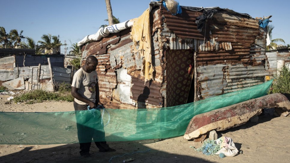 Jose Martinho, 43, repairs his fishing nets in Nova Praia neighbourhood, in front of his home. He and his family were severely affected by Cyclone Idai a year ago.