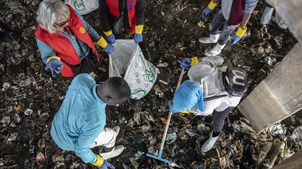 Sudanese refugees Omar (left) and Mawadda (right) load waste into bags.