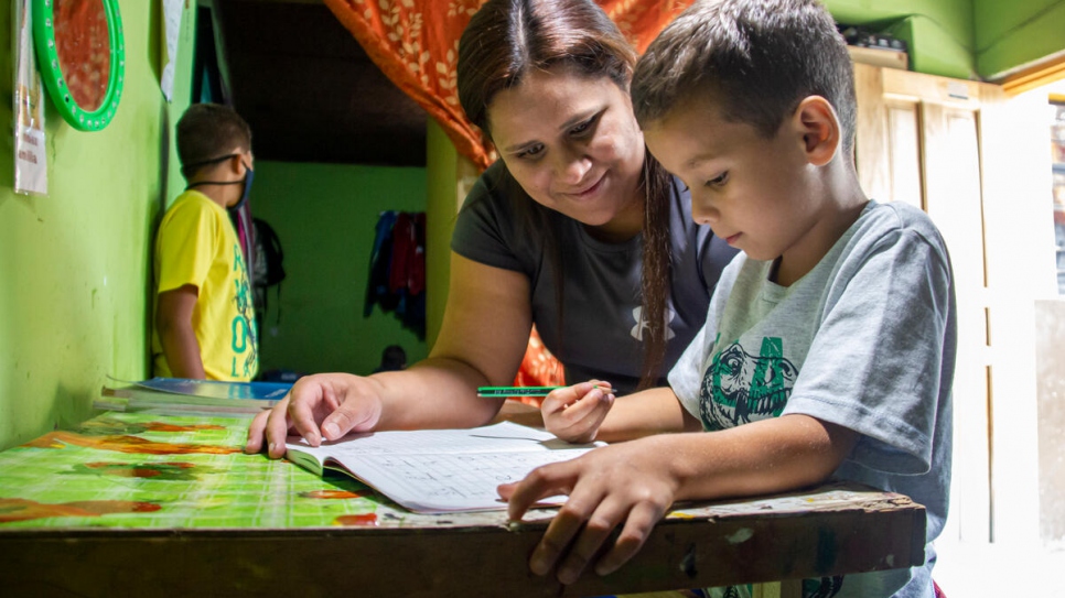 María José Mercado ayuda a uno de sus hijos con la tarea. Regularizarse ayudará a que sus hijos completen su educación en Ecuador.