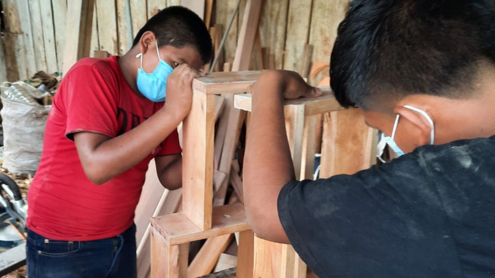 Dos jóvenes solicitantes de asilo practican lo que han aprendido en las clases de carpintería / carpintería de HUMANA.