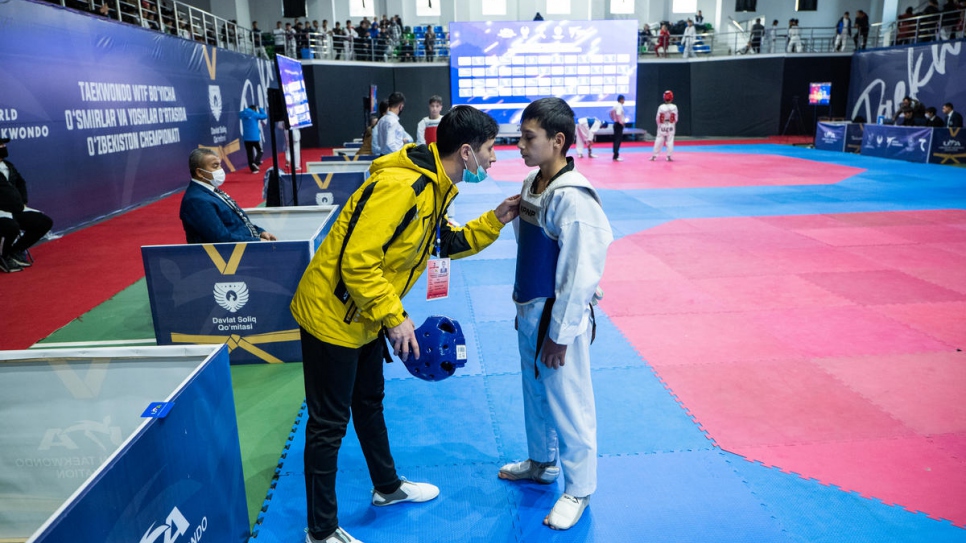 Mukhamadjon da instrucción a un alumno durante un torneo de taekwondo.