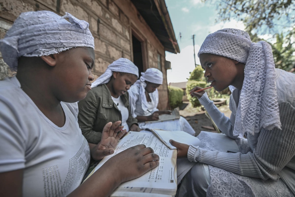 Nozisi Reuben Dube (à droite), membre de la communauté shona et apatride, aide ses soeurs (de gauche à droite) Janet, Tema et Brenda à faire leurs devoirs, devant leur maison à Kinoo au Kenya. Novembre 2020. 