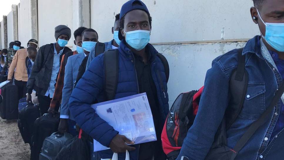 Un grupo de solicitantes de asilo se sube a los autobuses que los llevarán al aeropuerto internacional de Trípoli para un vuelo de evacuación humanitaria hacia la seguridad en Ruanda.