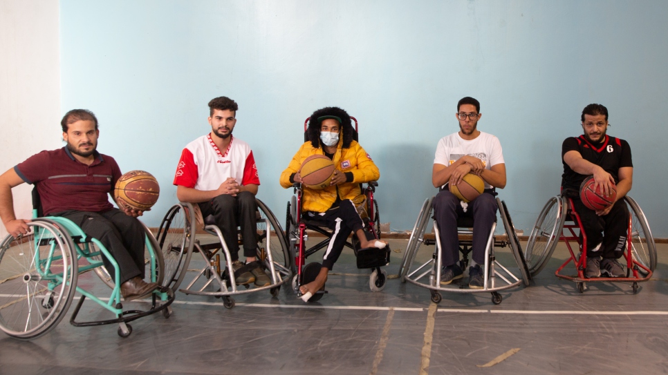 Mohamed (en jaune) se fait photographier avec d'autres personnes en fauteuil roulant après les avoir regardées jouer au basket. 