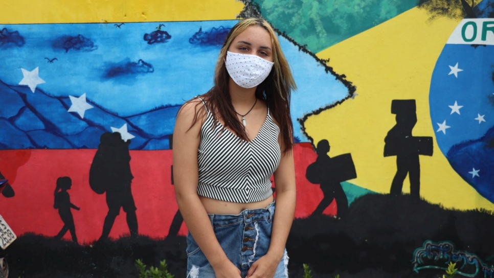 Amy en la entrada del albergue temporal Rondon 2, frente al mural pintado por su hermano Anthony para representar el flujo de refugiados y migrantes venezolanos hacia Brasil. 