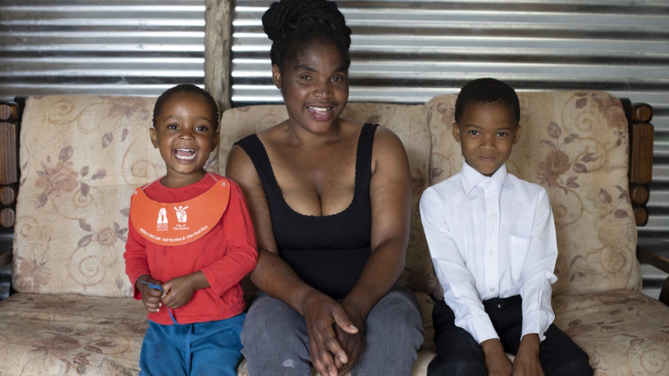 Mpho Modise pose avec ses deux filles Keitumestsi et Thabang, dans leur logement à Brits, en Afrique du Sud. 