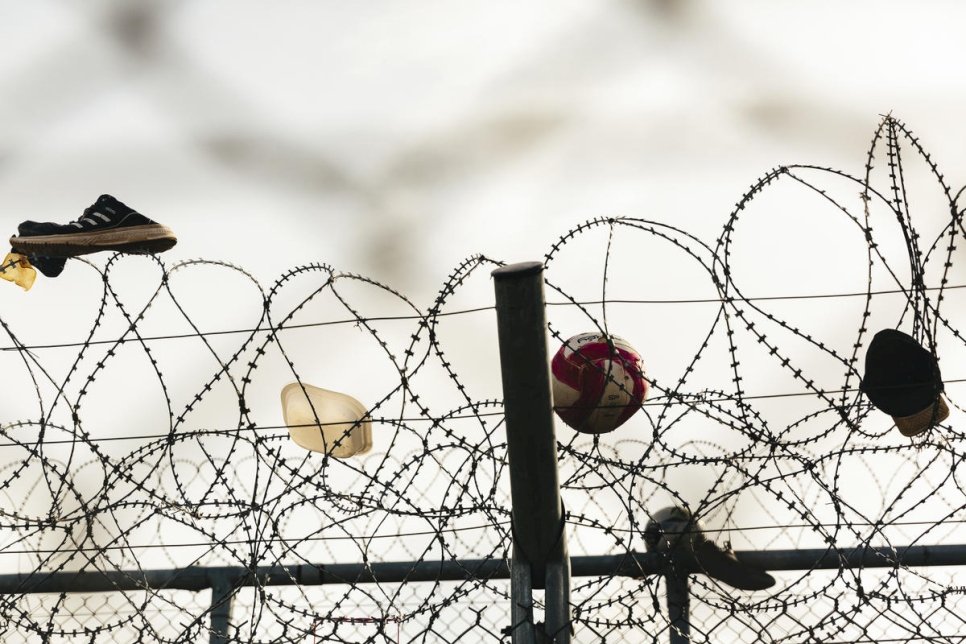 Des chaussures, un ballon et une casquette pris dans une clôture en fil de fer barbelé au centre de réception et d'identification de Fylakio, près de la frontière entre la Grèce et la Turquie. 