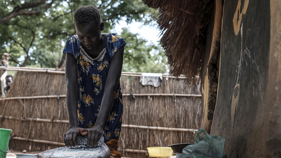 Nyamach Lul, 16 ans, écrase des grains de maïs pour en faire de la farine devant l'abri qu'elle partage avec sa soeur âgée de 13 ans dans le camp de réfugiés de Jewi, en Éthiopie. Nyamach et sa soeur sont des mineures non accompagnées. 