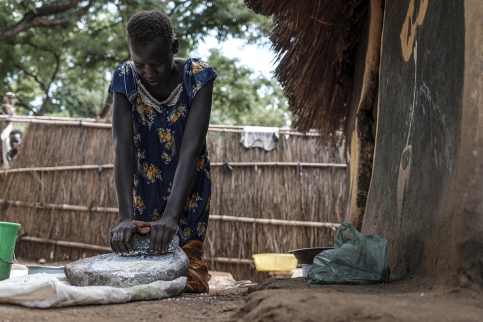 Nyamach Lul, de 16 años, machaca granos de maíz en harina fuera de la casa que comparte con su hermana de 13 años en el campamento de refugiados Jewi de Etiopía. Nyamach y su hermana son menores no acompañadas. 