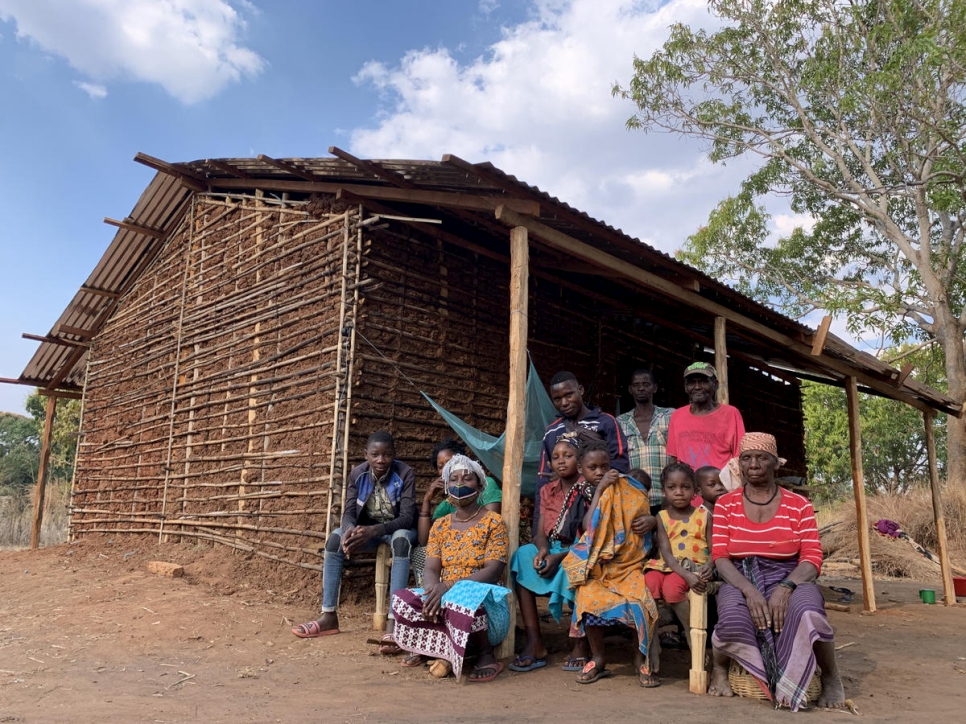 Joaquina* (con máscara) se sienta con su familia y parientes fuera de la casa de su hermano en Montepuez después de huir de ataques violentos en el norte de Mozambique. 