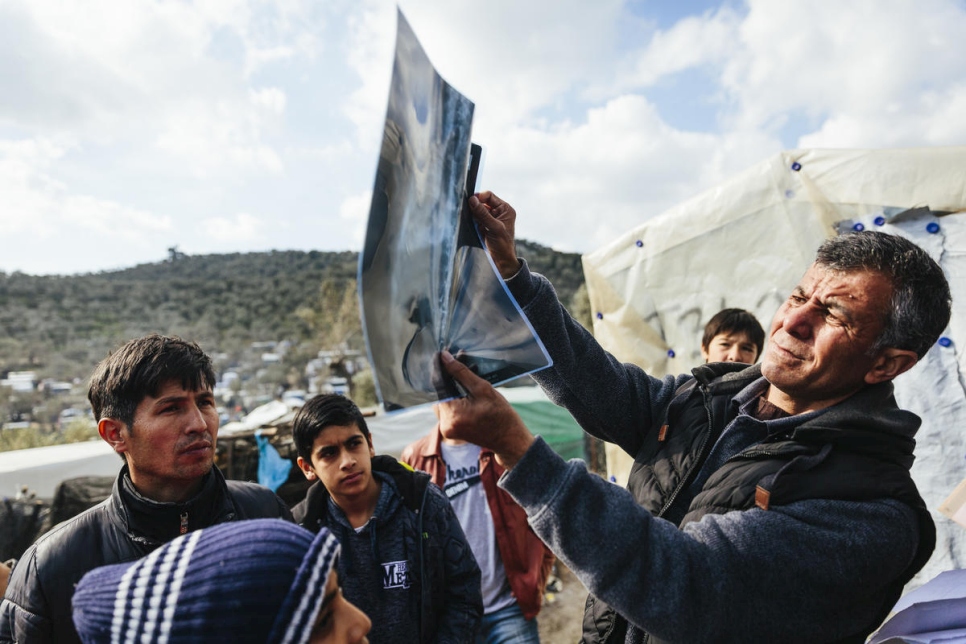 Sardar, un médico que huyó de Afganistán tras recibir amenazas de muerte, examina las placas de un solicitante de asilo con cáncer en el centro de recepción e identificación de Lesbos.