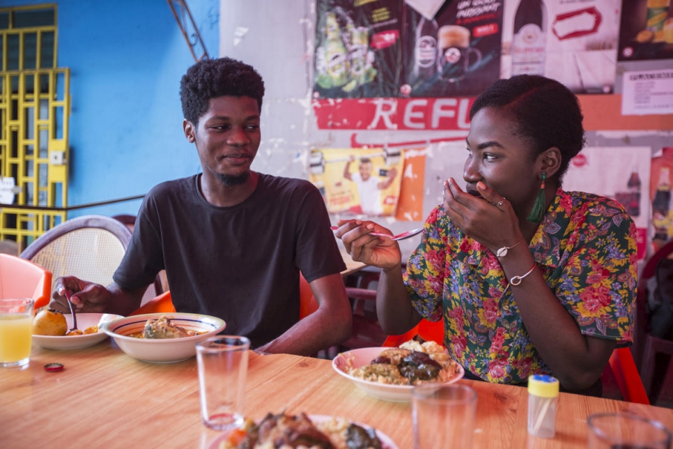 El diseñador gráfico marfileño O'Plérou disfruta de una comida tradicional con una amiga en un restaurante de comida popular en Abidjan, Côte d'Ivoire. 