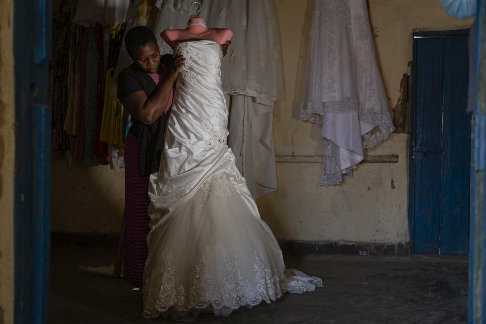 La refugiada congoleña Neema Claire, una de las cientos de mujeres apoyadas por Francoise Sabuni Chikunda, muestra uno de los vestidos de novia que hizo en el asentamiento de Nakivale, Uganda. 