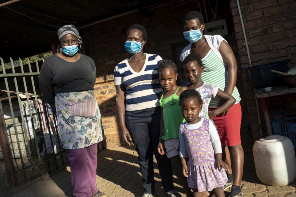 Una familia de Zimbabwe se encuentra frente a su alojamiento en Pretoria Norte, después de recibir alimentos de la comunidad empresarial de refugiados somalíes. 