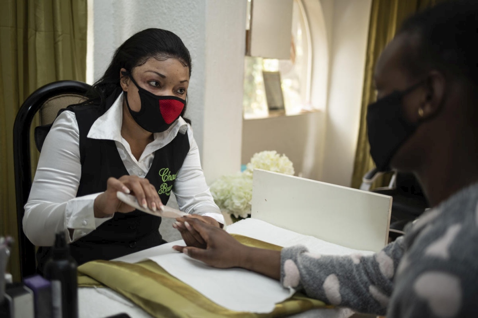 Michelle, refugiada congoleña, le hace una manicura a una clienta en su salón de belleza en Pretoria, Sudáfrica. 
