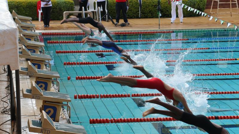 a group of Para swimmers dive into a pool