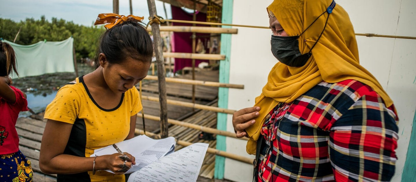 Almalyn Akmad (pashmina amarilla) proporciona certificados de registro de nacimiento a otra mujer bajau en Kasanyangan, ciudad de Zamboanga, Filipinas.