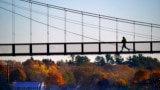 A jogger crosses the Swinging Bridge over the Androscoggin River on a frosty autumn morning, Nov. 4, 2021, in Brunswick, Maine. 