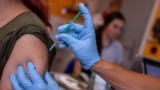 A doctor vaccinates a woman with a COVID-19 vaccine, in his office in Berlin, Germany, Nov. 2, 2021.