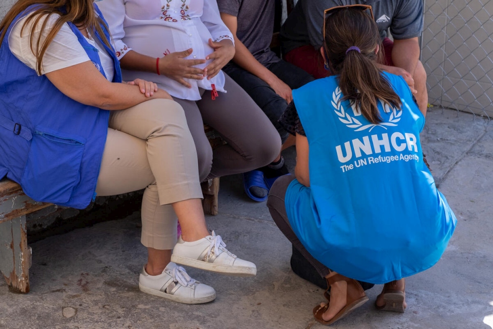 Two UNHCR staff members speak with asylum-seekers in a border town in northern Mexico.