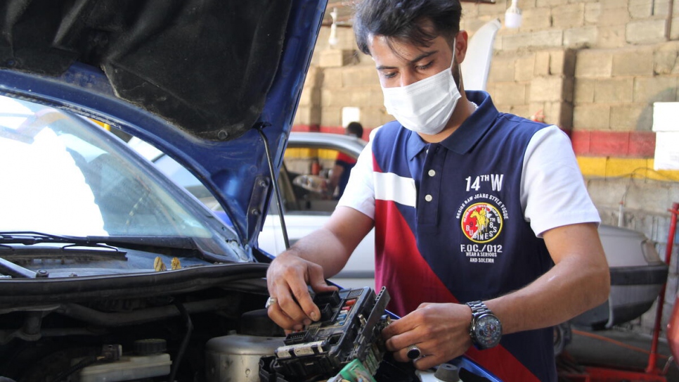 Danial checks the electrical wiring on a customer's car.