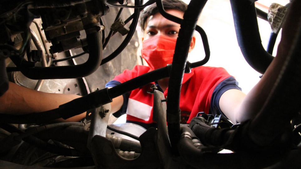 Soleiman inspects an engine at the repair-shop where he currently works as an apprentice. 