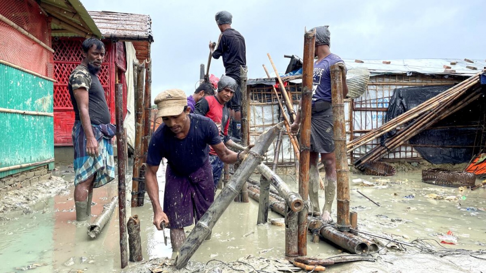 Rohingya refugee volunteers work to re-build a bamboo bridge destroyed by floods.