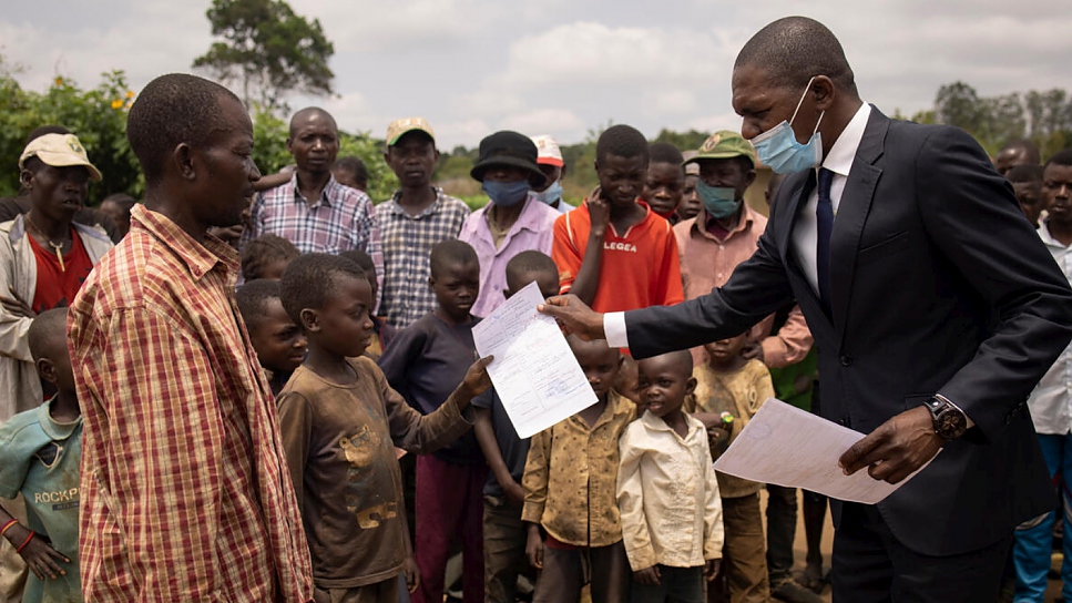 Justin Assomoyi, director for the promotion of indigenous people's rights at the Ministry of Justice, hands over a late birth certificate to a young indigenous boy in Ngoulayo site, on 13 September 2021. 