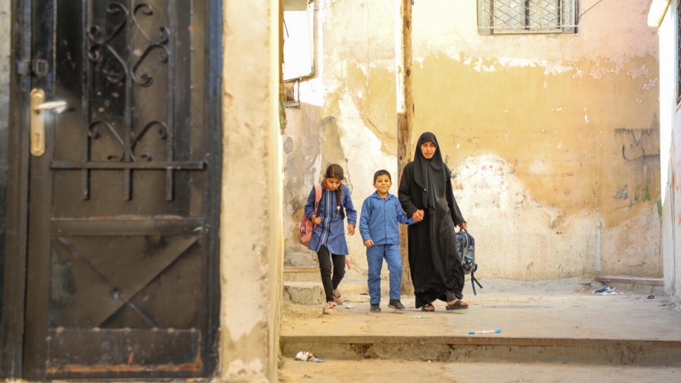Aisha, 10, and Ahmed, 8, walk home with their aunt Huda before the recent closure of schools due to COVID-19.