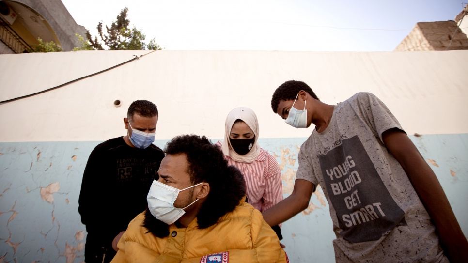 Mohamed is helped by his brother Yusuf (in grey) to test his new wheelchair, with staff from the NGO Humanity & Inclusion in Tripoli.