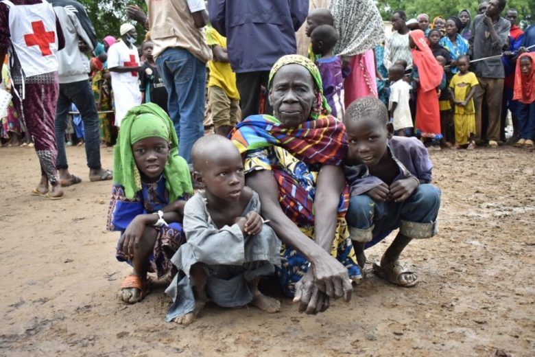 A family sitting outside on a muddy floor.