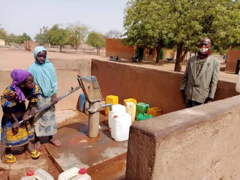 two girl taking water from well