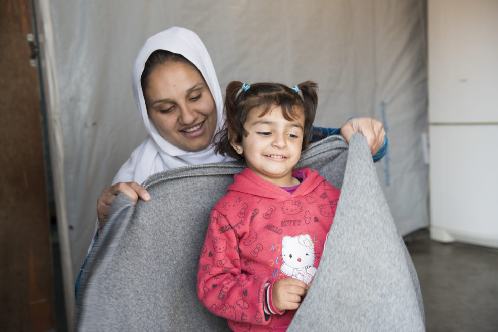 Mother wraps her daughter in a grey blanket from a winter assistance package