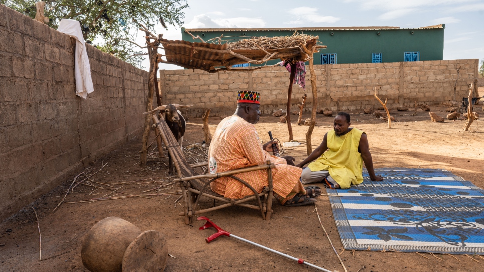 Madiega est assis avec son voisin, Soumaila Ourdraogo, qui a accepté d'accueillir deux familles déplacées sur ses terres. 