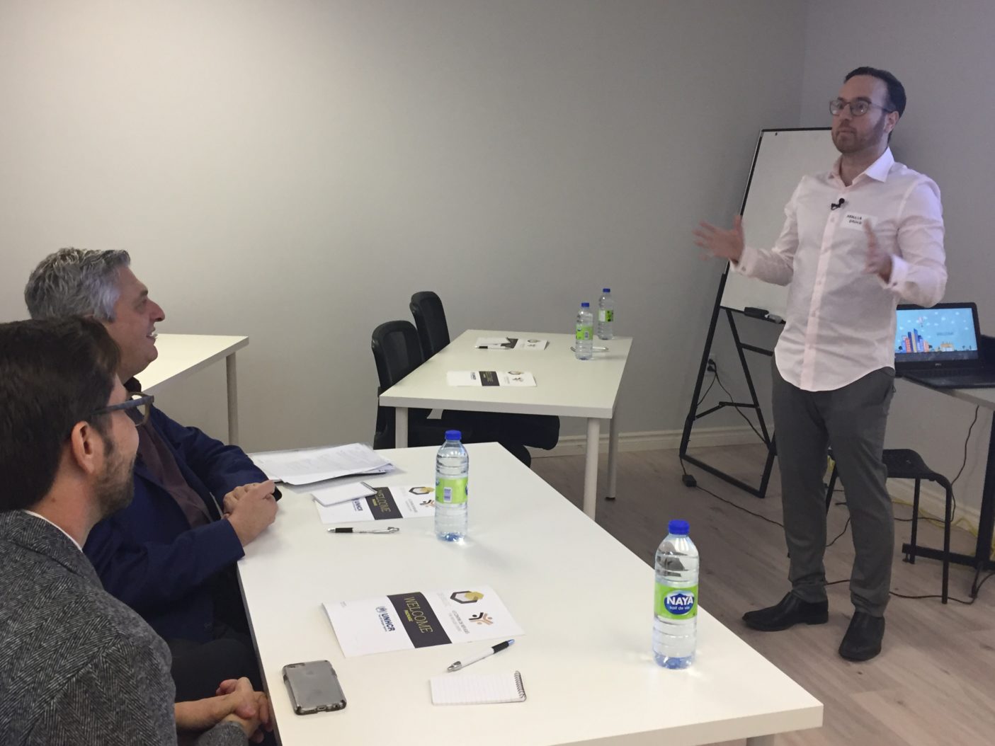 The High Commissioner for Refugees, Filippo Grandi and Representative in Canada Jean-Nicolas watch a presentation by DevBloc Executive Director Abdulla Daoud at The Refugee Centre in Montreal.