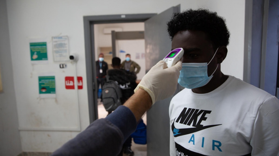 Asylum-seekers from Somalia, Eritrea and Sudan get temperature checked before boarding a humanitarian evacuation flight out of Libya to Rwanda.