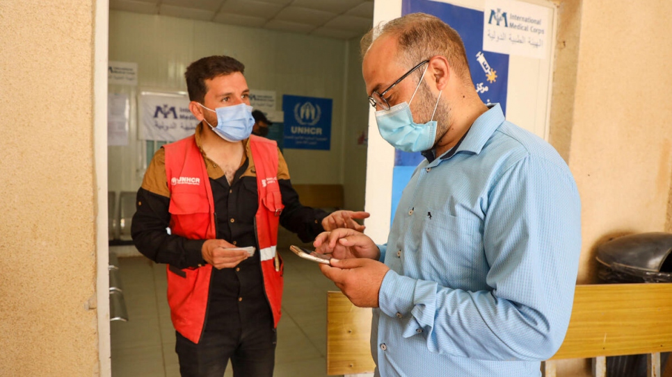 Sameeh, 32, helps a fellow refugee in the camp register to receive the COVID-19 vaccine.