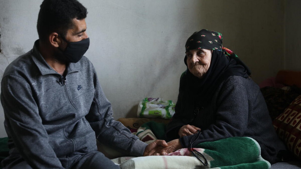 Amina, 85, sits on the bed with her son Abdo at the home they share in Touline, Lebanon.