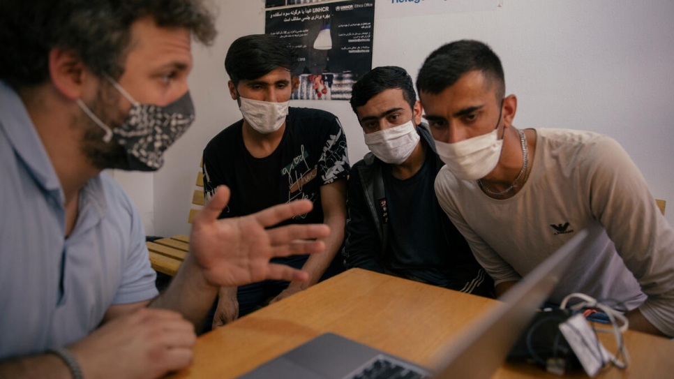 Nikola Kovačević talks to two Afghan asylum-seekers through an interpreter at a reception centre in Adasevci.