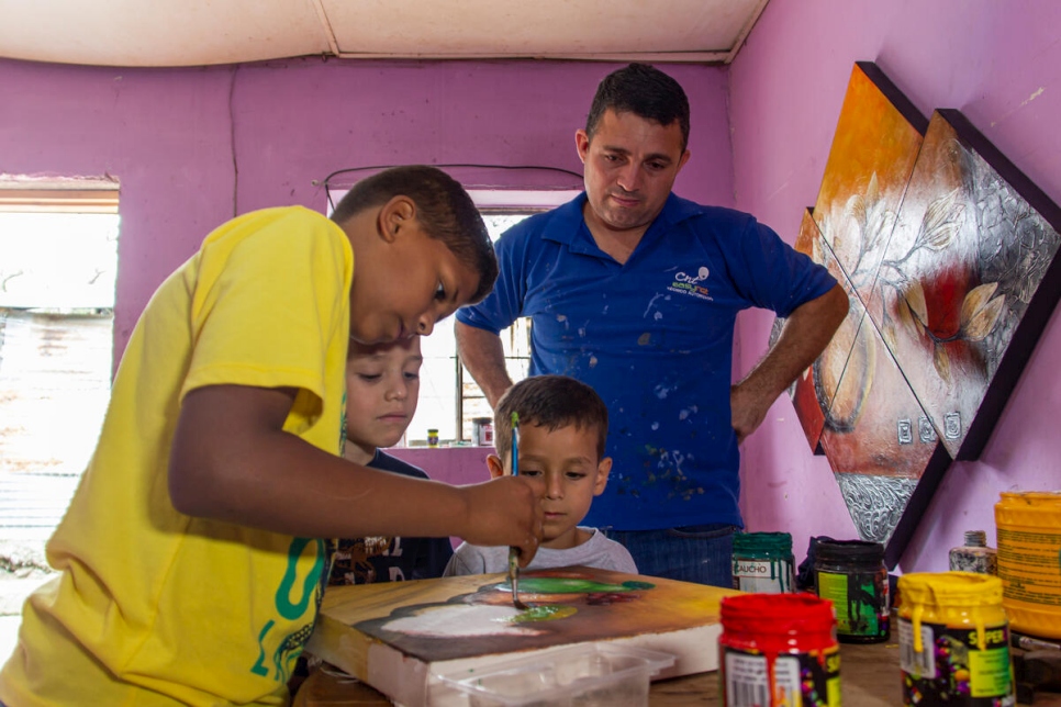 José Soto supervises while his oldest son paints one of the canvases the family sell to earn an income.