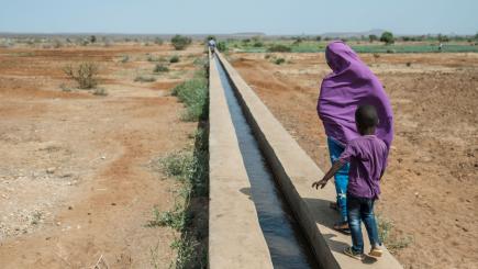 A girl and a boy walk along a canal in an irrigated farming land in Melkadida, Ethiopia.