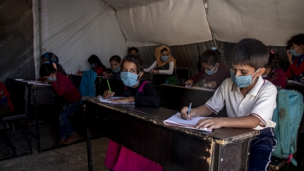 Children sitting at school desks in a tent