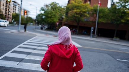 Woman with her back to the camera, waiting to cross a road