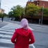 Woman with her back to the camera, waiting to cross a road