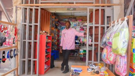 Returnee standing in front of shop