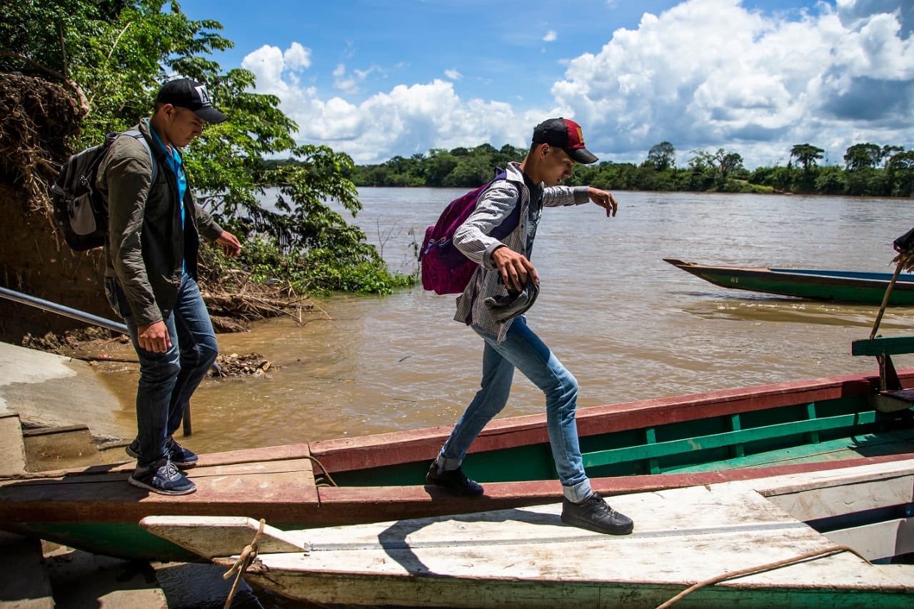 two men walk across boards over the water