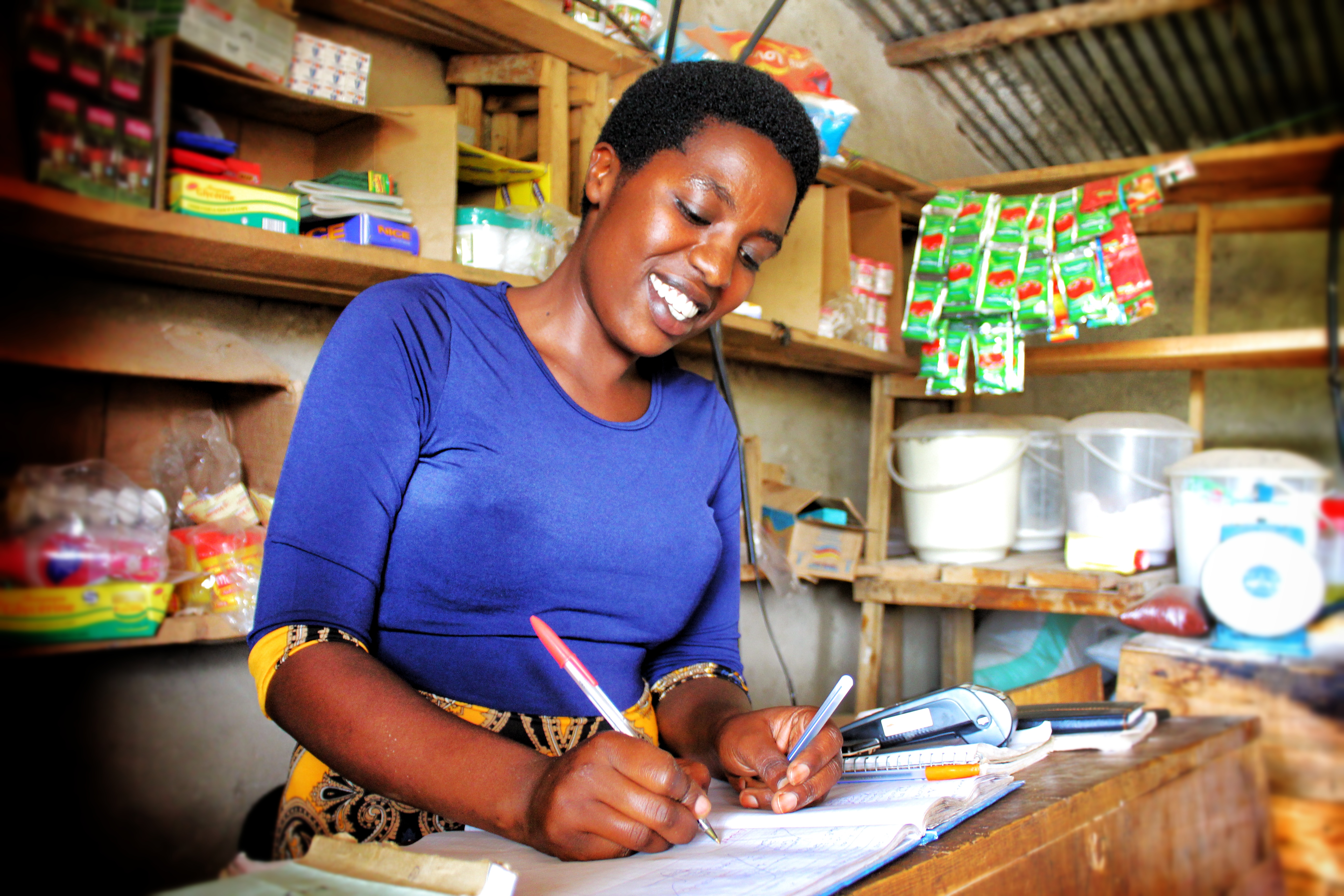 A woman is standing in a shop writing 